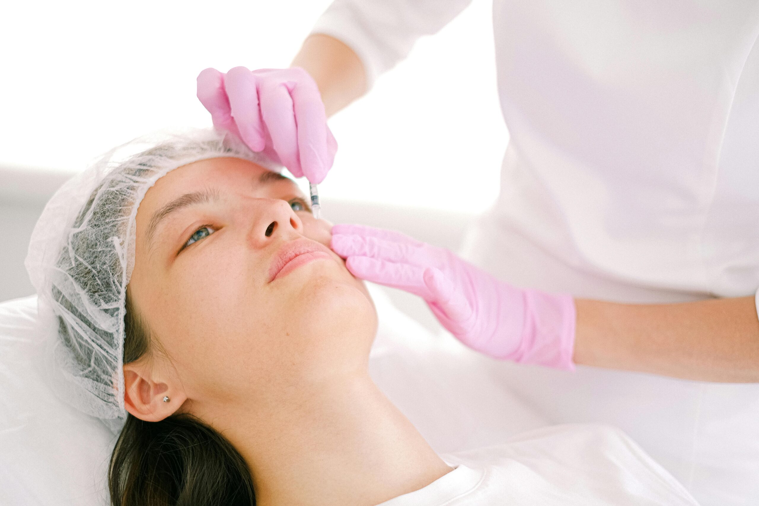 Close-up of a woman receiving anti-wrinkle treatment to the forehead by a medical aesthetics practitioner.