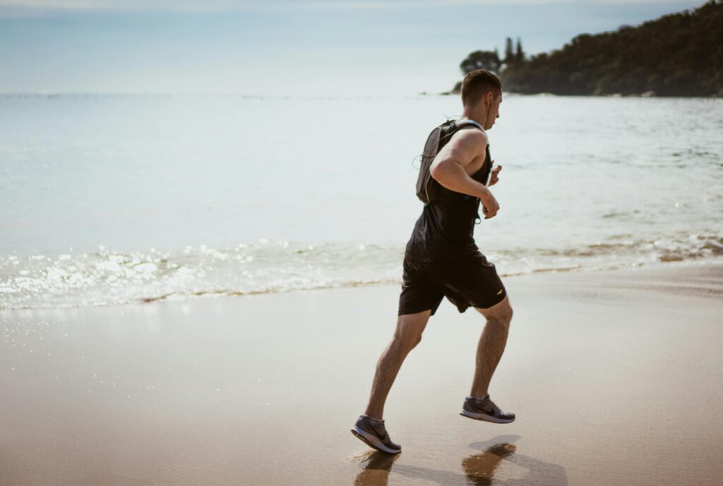 Middle-aged man running on a beach representing vitality, energy, and healthy testosterone levels