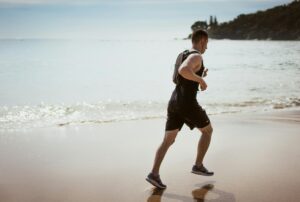 Middle-aged man running on a beach representing vitality, energy, and healthy testosterone levels